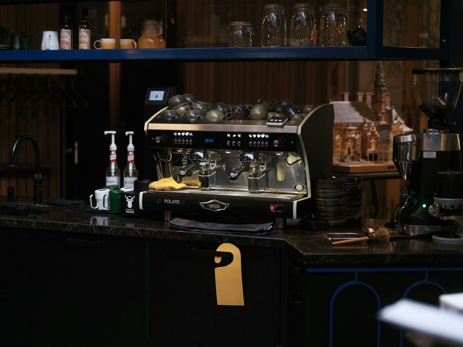 Espresso machine, cups and coffee grinders on a café counter.